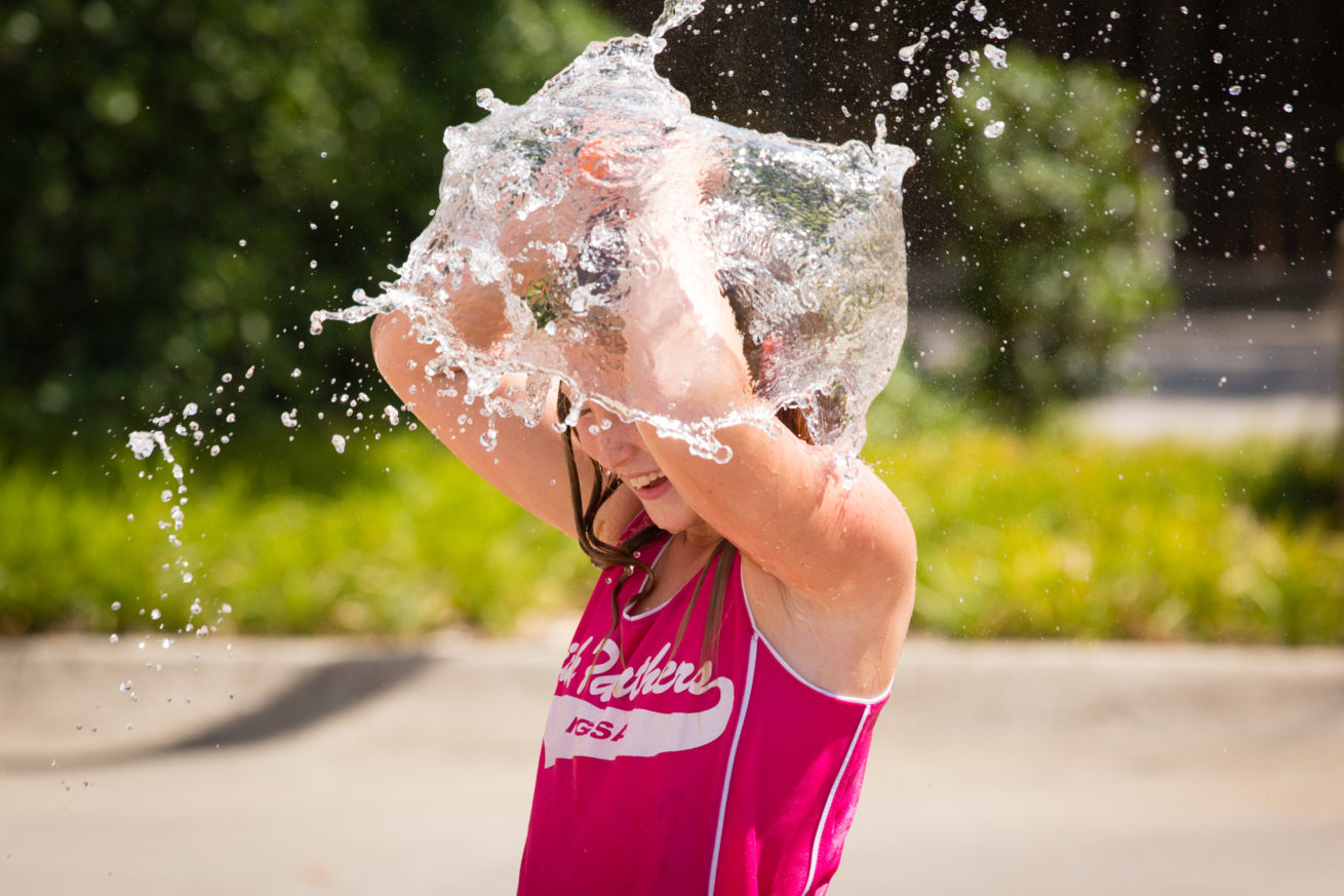 Daisy Harder pops a water balloon over her head to keep cool during a water balloon fight at the South Branch Library.   Denton County is under a heat advisory as temperatures reached a high of 101 degrees.